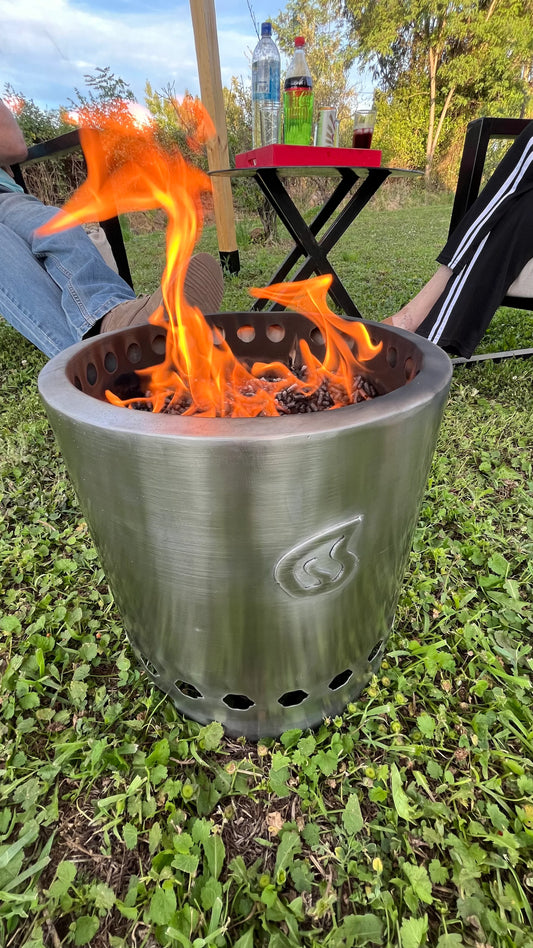 Brasero metálico Humos con llamas activas para camping al aire libre sobre césped verde