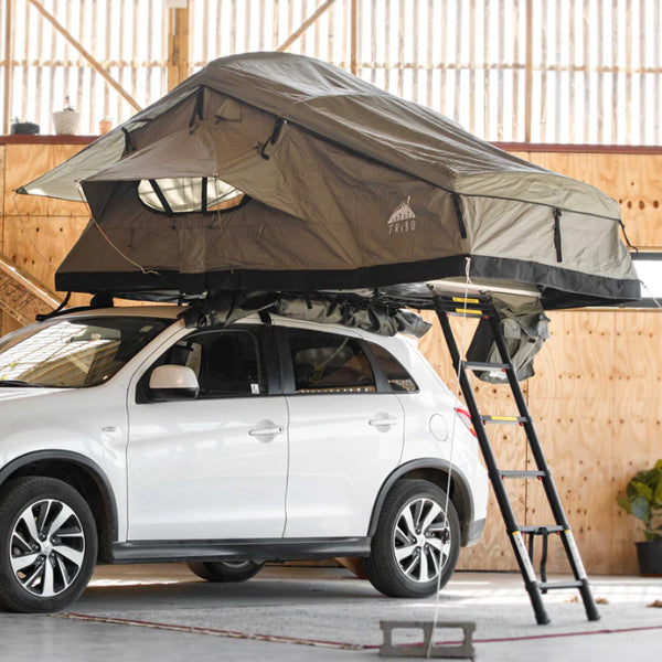 Tribu Carpa de Techo rooftop tent mounted on white SUV with ladder extended indoors