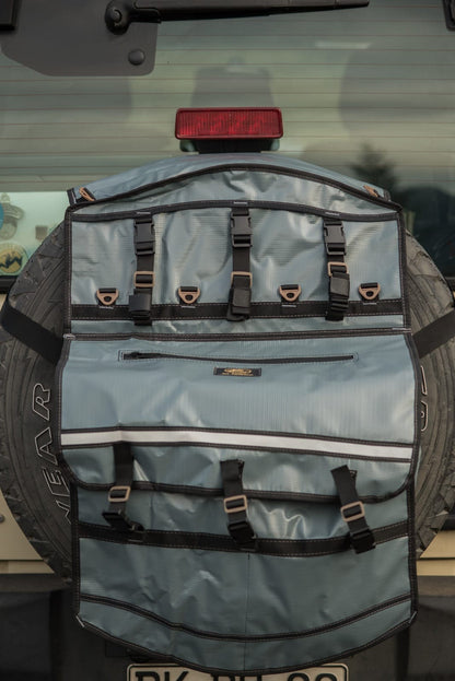 Bolso Para Neumático gris con múltiples correas y compartimentos fijado a una rueda trasera de vehículo