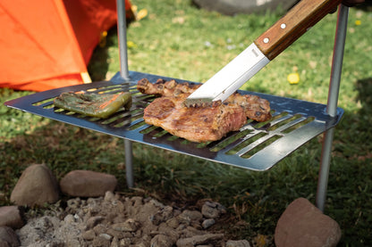 Parrilla Camping Humos con carne y pimiento asándose sobre fuego al aire libre en un campamento