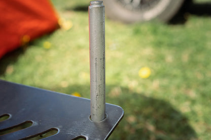 Close-up of Humos Parrilla Camping grill metal support pole on outdoor grass background